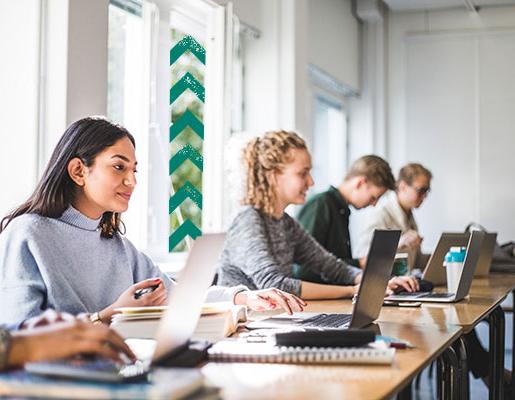 坐在教室里使用笔记本电脑的学生